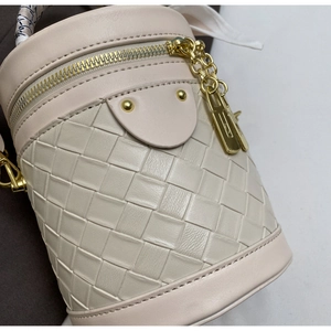 Detail of quilted woven cylinder bucket bag with gold hardware and silk scarf handle