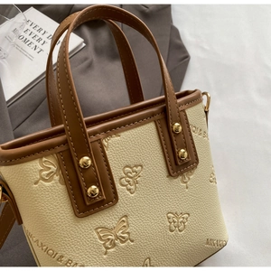 Detailed close-up of cream textured leather handbag with embossed butterfly patterns