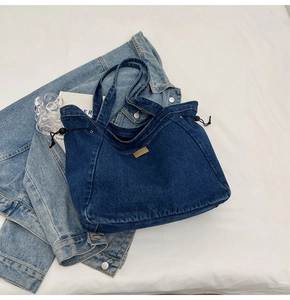 Detail der dunkelblauen Denim-Tragetasche mit Kordelzugverschluss und khakifarbenem Lederpatch