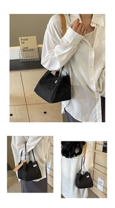 Detail of black denim bucket bag with dual handles and contrast shoulder strap