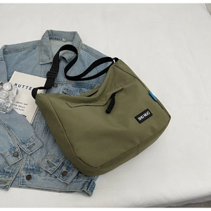 Detailed macro view of olive green canvas messenger bag with brand logo and zipper