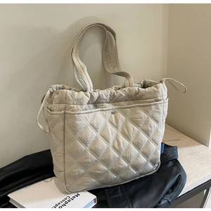 Gros plan d'un sac cabas en nylon beige matelassé avec cordon et poche à boucle métallique