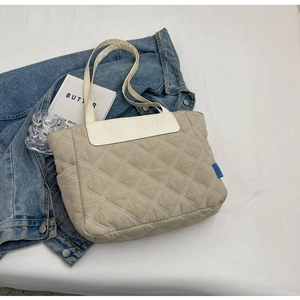 Detail of beige quilted tote bag with padded nylon fabric and logo embroidery