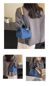 Detail of dark blue denim bucket bag featuring a street label and yellow leather strap