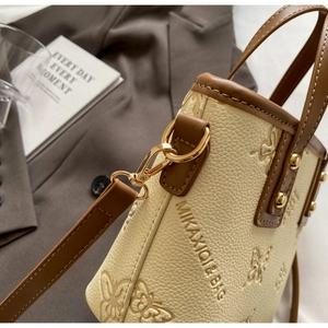 Detail showing lychee grain leather texture and embossed butterfly pattern with gold hardware