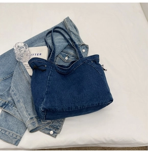Draufsicht auf eine dunkelblaue Denim-Tragetasche mit Kordelzug auf weißem Stoffhintergrund
