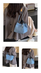 Close-up of light blue denim shoulder bag featuring hand made tag and leather joints