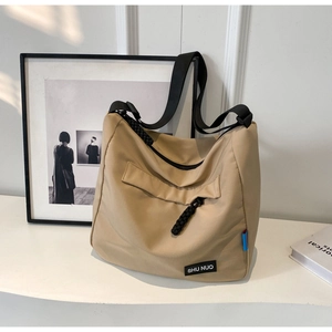Detailed macro view of khaki canvas tote with adjustable strap and brand logo patch