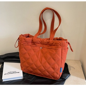 Gros plan du sac cabas matelassé orange avec surpiqûres losanges et poche à pression