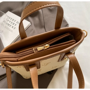 Top view of two-tone bucket bag featuring dual zippers, top handle, and bee embossing