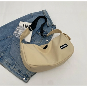 Detail der beigen Halbmondtasche mit schwarzem Schultergurt und FASHION-Logo auf Jeansjacke