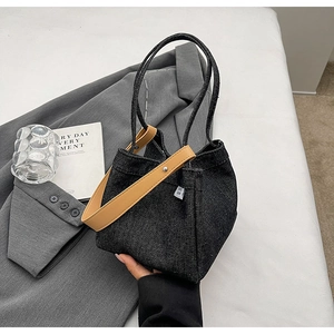 Close-up of denim bucket bag with leather handles and metallic buckle details
