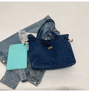 Detail der dunkelblauen Denim-Einkaufstasche mit Kordelzug, Metallösen und Lederaufnäher
