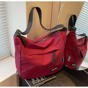 Detailed macro of burgundy tote with black adjustable strap and front zipper pocket