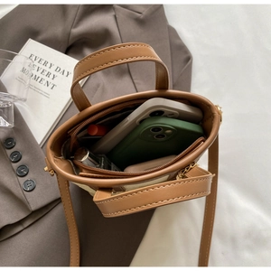 Interior view of brown bucket bag showing capacity for phones, lipstick and perfume