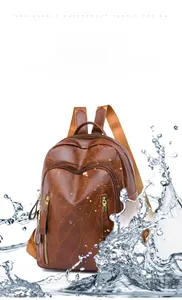 Waterproof PU leather backpack in brown showing water splash protection feature