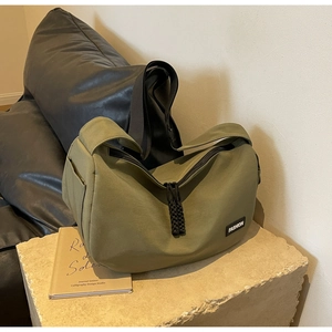 Detail der olivgrünen Utility Umhängetasche mit Fashion Label auf Steinsockel