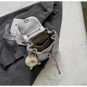 Détail du mini sac à dos matelassé argenté avec cordon rose et accessoire en peluche