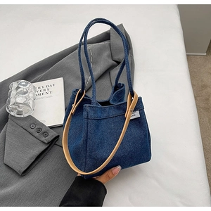 Chic denim bucket bag with brown leather accents shown in a high-fashion lifestyle setting