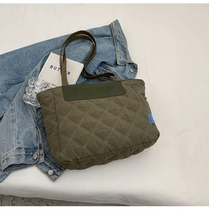 Detail of army green quilted tote bag featuring diamond stitching and brand leather patch