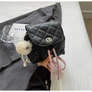 Détail d'un mini sac à dos noir matelassé avec fermoir argenté et bretelles roses