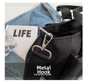 Detail showing the durable silver metal hook and black canvas strap of the tote bag