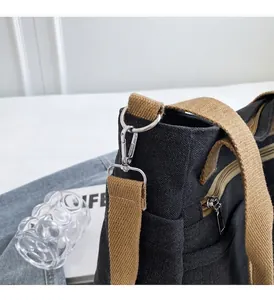 Détail d'un sac en toile noire avec quincaillerie en argent et bandoulière marron