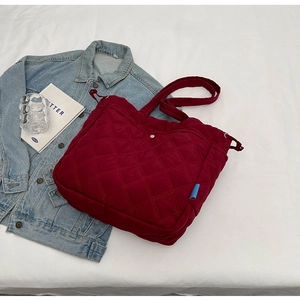 Détail du sac fourre-tout en nylon bordeaux matelassé avec motif à losanges et étiquette