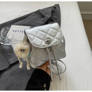 Détail d'un mini sac à dos argenté matelassé avec bretelles chaîne et bijou de sac