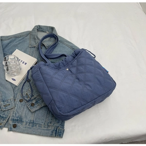 Détail du sac cabas bleu matelassé avec motif à losanges et cordon de serrage