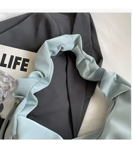 Close-up of mint blue crescent bag showing pleated handle design and silver metal zipper