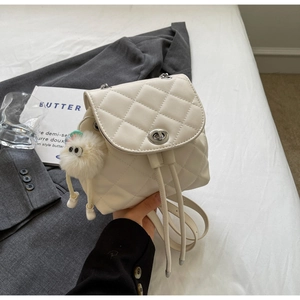 Détail d'un sac à dos blanc matelassé avec bandoulière chaîne et charm en peluche