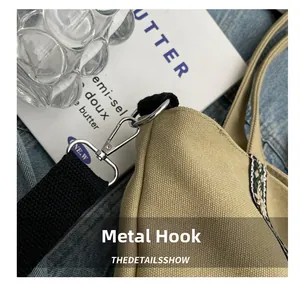 Detail of durable silver metal hook and black woven strap on a khaki canvas tote bag