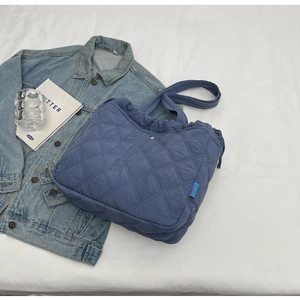 Détails du sac cabas matelassé bleu avec surpiqûres losanges et étiquette de marque