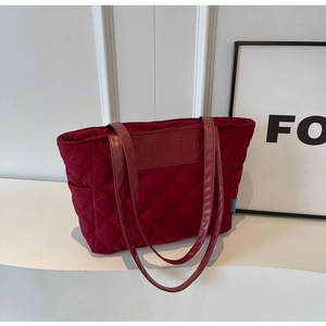 Close-up of wine red quilted tote bag with diamond pattern and branded leather patch