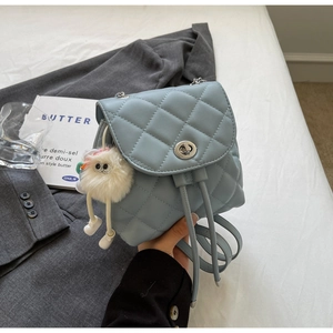 Détail du mini sac à dos matelassé bleu clair avec fermoir rotatif et breloque peluche
