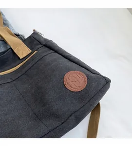 Gros plan du sac en toile avec écusson logo en cuir marron et fermeture éclair en métal