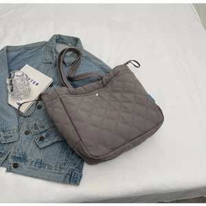 Détail d'un sac cabas gris matelassé avec motif losange et texture en nylon doux
