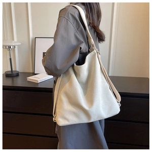 Off-white large capacity tote bag with wide shoulder strap shown on model in studio