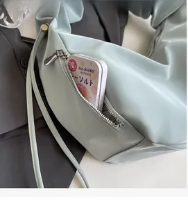 Detail of mint green dumpling bag showing front zipper pocket and pleated shoulder strap