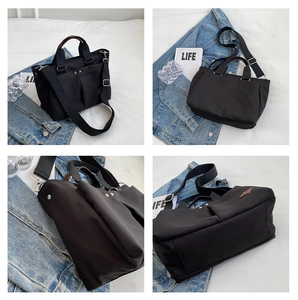 Detail view of black canvas tote showing multiple pockets, rivets, and adjustable strap