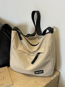 Large beige nylon tote bag with black adjustable straps on a minimalist stone base