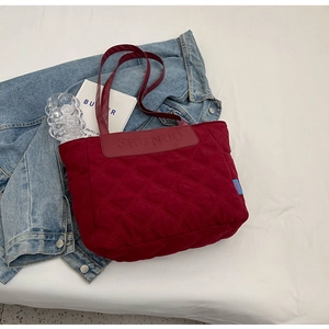 Detailed close-up of quilted diamond pattern and logo on burgundy shoulder bag