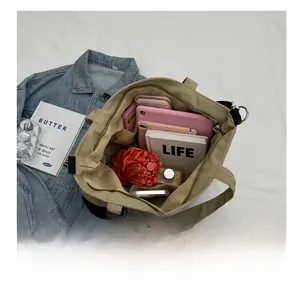 Top view of spacious khaki canvas tote interior holding a tablet, wallet, and water bottle
