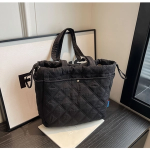 Détail d'un sac cabas noir matelassé avec cordon latéral et poche à bouton métal