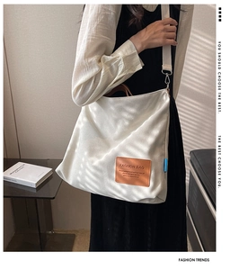Detail of off-white canvas tote bag featuring brown leather patch and premium metal hardware