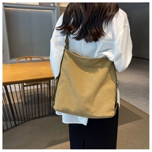 Detail of large khaki canvas bag showing material texture and adjustable strap on shoulder