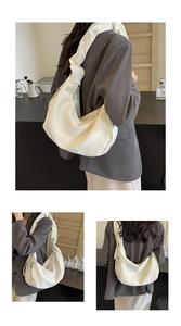 Detail of white glossy crescent bag with unique knotted wide shoulder strap and silver zipper
