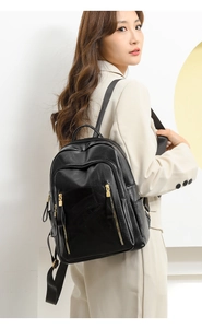 Detail of black leather backpack with gold zippers shown on a female model