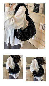 Detailed view of glossy black pleated shoulder bag with shiny mirror finish and silver zipper